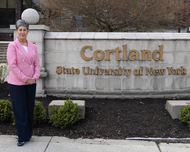 Ann McClellan poses near the Cortland sign at the Miller Building
